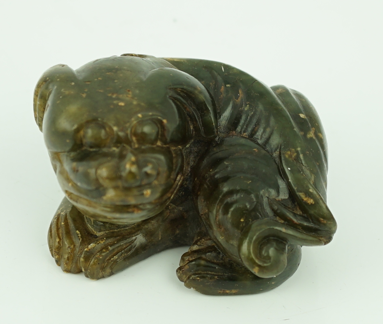 A Chinese Ming green soapstone figure of a recumbent lion-dog, 16th/17th century